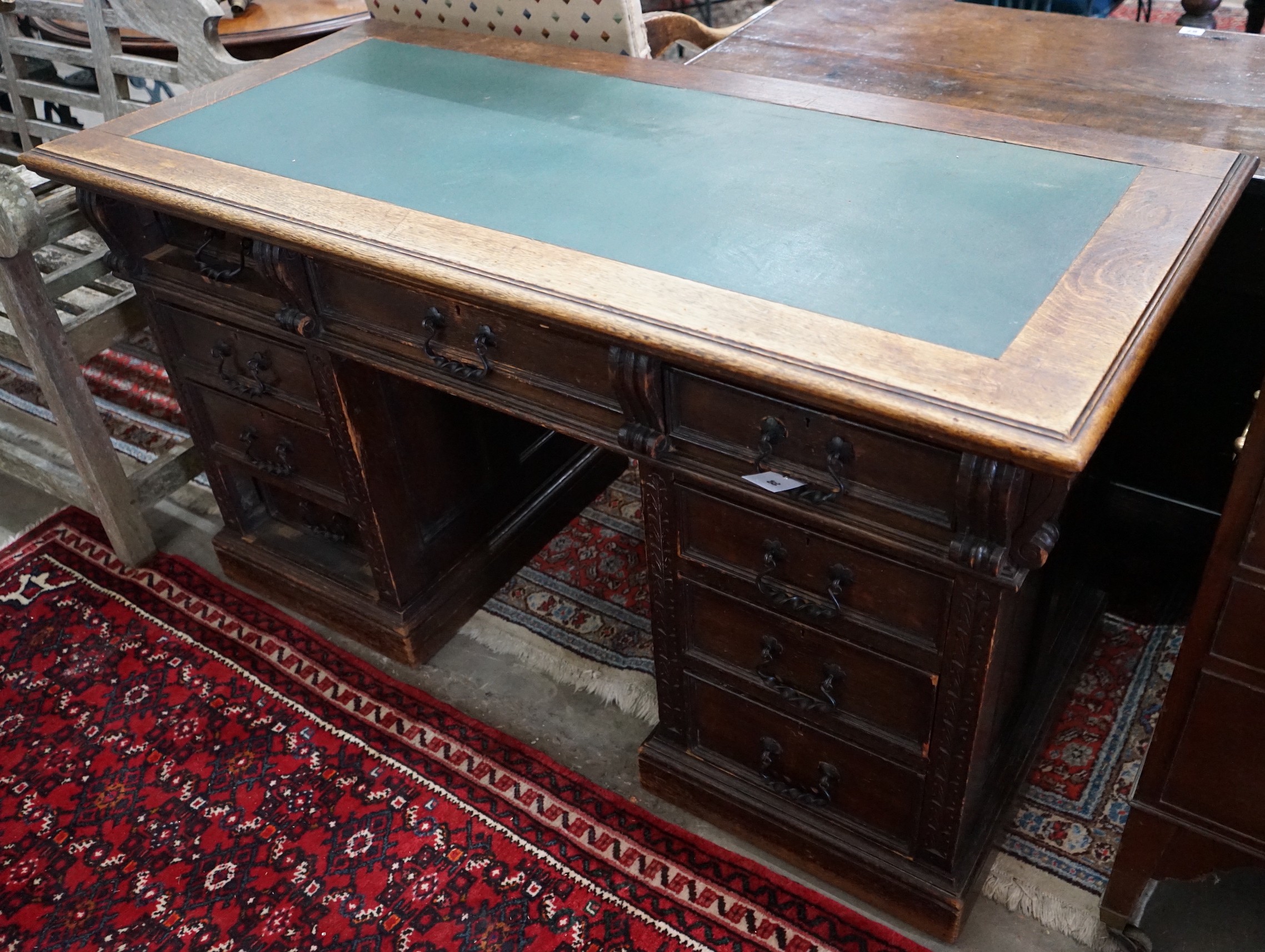 A late Victorian carved oak pedestal desk, length 137cm, depth 65cm, height 77cm